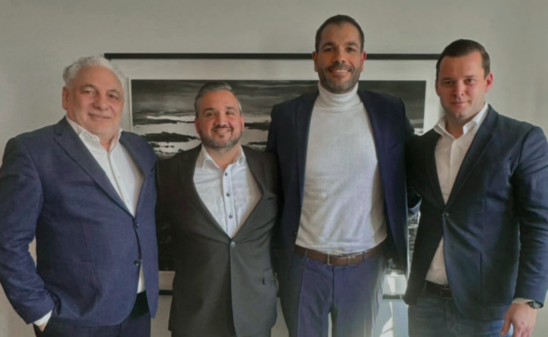 Four business leaders standing together and smiling – representing the integration of Swiss Cloud Computing AG into the CONVOTIS Group.