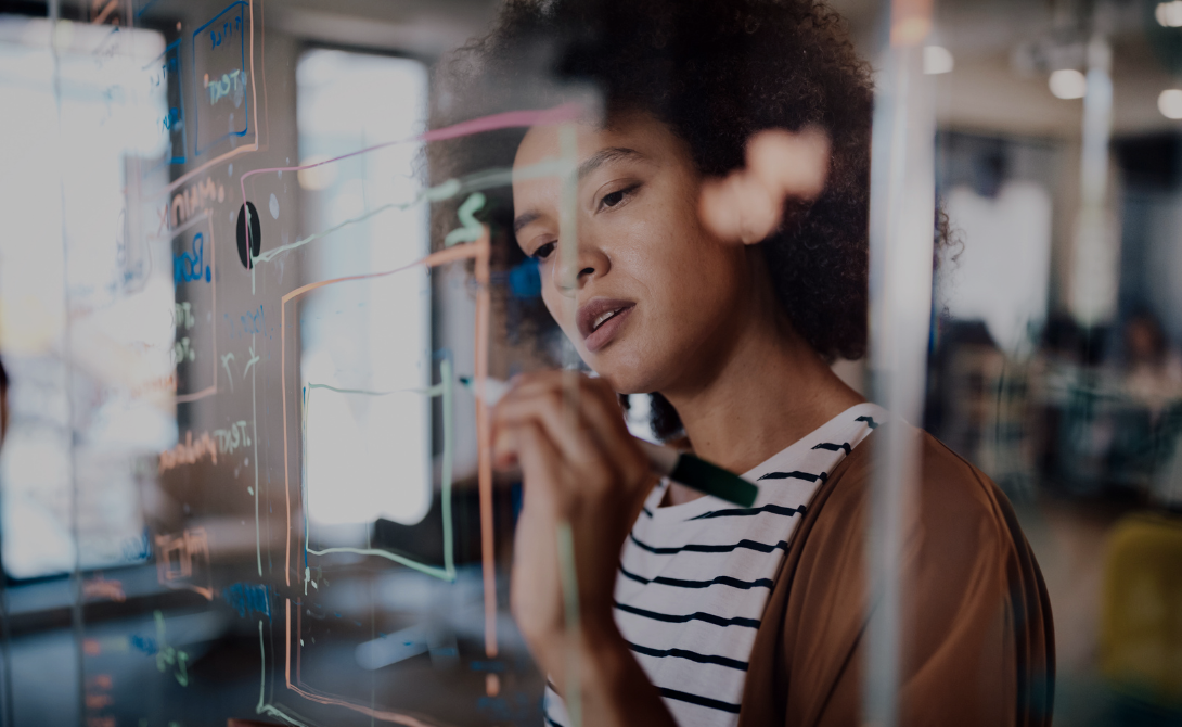 Woman planning integration workflows on a glass board – focused on streamlining automation and system logic in IT projects.