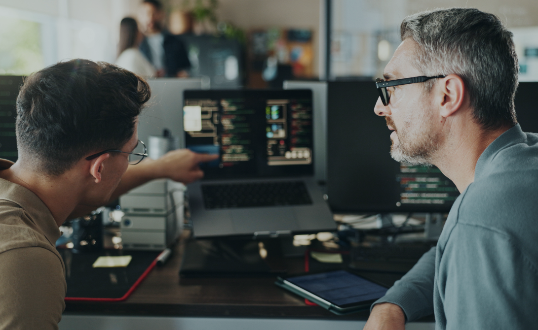 Two developers analyzing legacy code and planning application modernization on dual screens