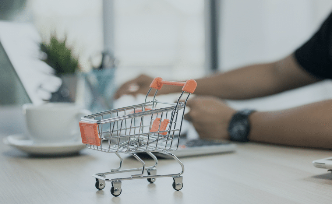Mini shopping cart on a desk in front of a laptop – symbolizing e-commerce performance, conversion optimization, and online retail technology.