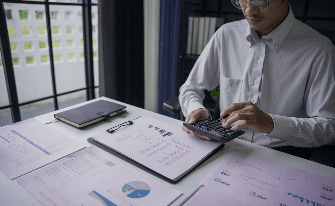 Cloud cost manager reviewing budgets and workloads using calculator and reports.